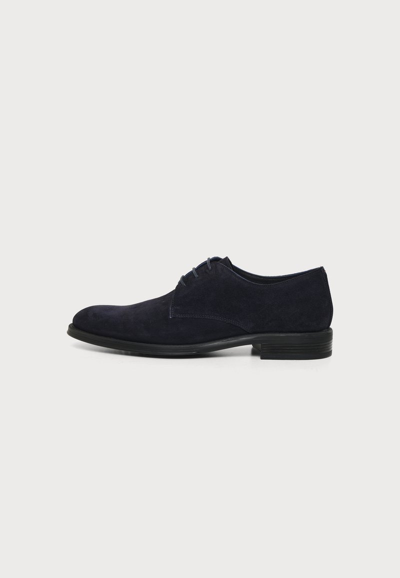 Chaussure habillée montante en daim noir pour homme avec petit talon empilé et bout arrondi lisse, vue de profil sur un fond uni.