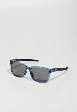 Blaue transparente quadratische Sonnenbrille mit dunkelgrauen Gläsern und schwarzen Bügeln. Mit einem geprägten Logo an der Seite.