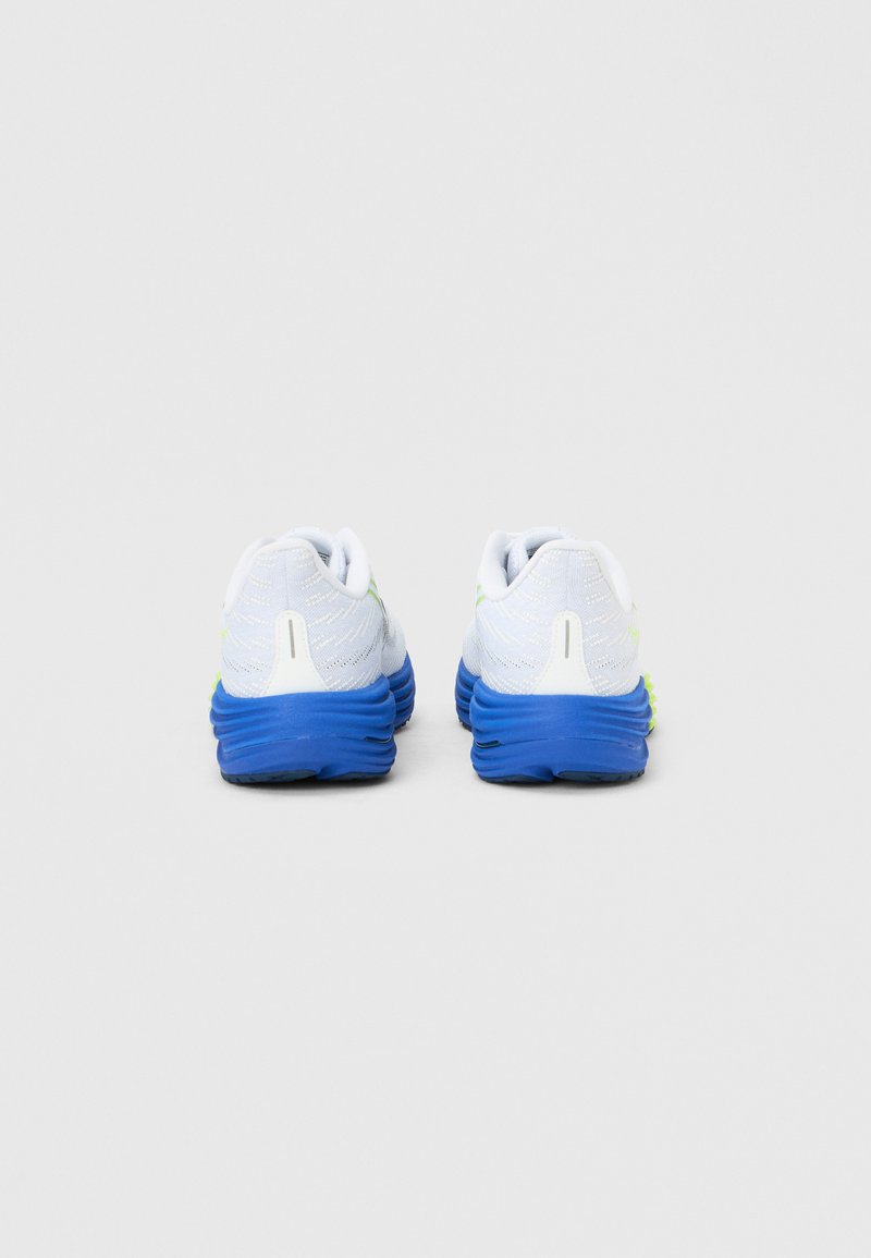 Chaussures de course blanches avec semelles bleues, dotées d'accents jaunes, d'une tige en mesh texturé et d'un talon rembourré pour le soutien.