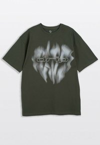Ciemnozielony T-shirt z krótkim rękawem z rozmytym białym abstrakcyjnym wzorem i konturowym napisem "drip" na klatce piersiowej.