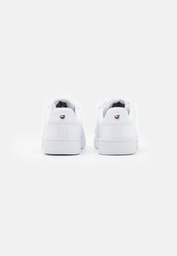 Białe sneakersy z teksturowanym siateczkowym tyłem, okrągłym czubkiem i płaską gumową podeszwą; posiadają mały metaliczny akcent na pięcie.