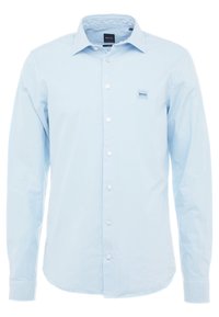 Světle modrá košile s dlouhým rukávem, límečkem na knoflíky, bílými knoflíky a malou nášivkou s logem na levé straně hrudi. Hladká textura látky.