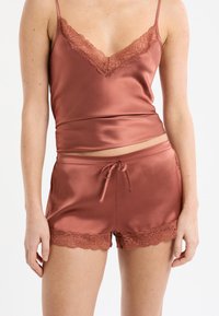 Satin-Loungewear-Set in warmem Rosaton mit Spitzenverzierung, bestehend aus einem Spitzenbesetzten Camisole und passenden Shorts mit Tunnelzugbund und Spitzenakzenten.