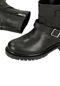 Schwarze Leder-Ankle Boots mit polierter Spitze, Schnallenriemen-Detail und einem Reißverschluss an der Seite. Robuste Sohle für Traktion und Haltbarkeit.
