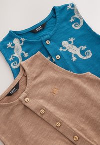 To ærmeløse beklædningsgenstande: en blå top med beige gekko-tryk og en brun top med solbroderi, begge med knaplukninger og tekstureret stof.