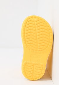 Semelle de chaussure en caoutchouc jaune avec un motif de grip en zigzag texturé et un bord supérieur blanc. Le style est décontracté et léger.
