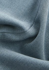 Strukturierter blauer Stoff mit einem subtilen Webmuster, der weiches, glattes Drapieren und eine Mischung aus hellen und dunklen Tönen zeigt.