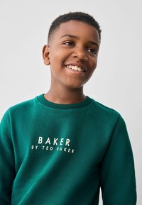 Zelená mikina s nápisom "BAKER by Ted Baker" v bielej farbe. Okrúhly výstrih a hladká textúra, vhodná na každodenné nosenie.