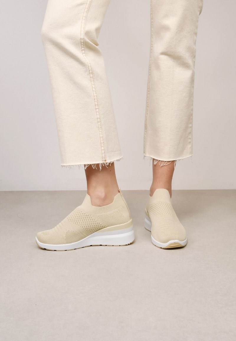 Chaussures à enfiler en tricot beige avec une tige texturée et une semelle plateforme blanche. Elles présentent un bout lisse et arrondi ainsi qu'un maintien élastique autour de la cheville.
