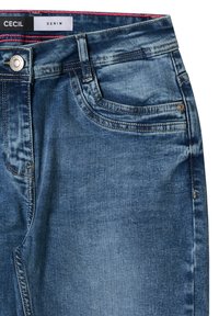 Jeans de mezclilla de lavado oscuro con una textura suave, que cuentan con un bolsillo delantero, botón de metal y costura contrastante en la cinturilla interior. Etiqueta de la marca visible.