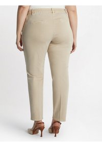 Beiga, figursydda byxor i ett mjukt tyg, med elastisk midja och två bakfickor. Matchade med ljusbruna högklackade skor.