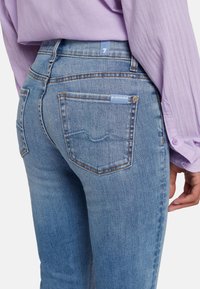 Jean en denim bleu clair au design ajusté. Caractéristiques de coutures robustes, deux poches arrière et une petite étiquette à la taille.