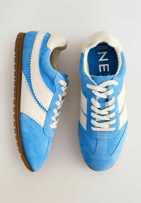 Blauwe suède sneakers met witte leren accenten, vetersluiting en een gestructureerde tussenzool; zachte voering aan de binnenkant voor extra comfort.