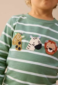 Grønstribet sweater med tre broderede dyrepatches: en giraf med pletter, en zebra og en løve. Blød tekstur og ribbet halsudskæring.