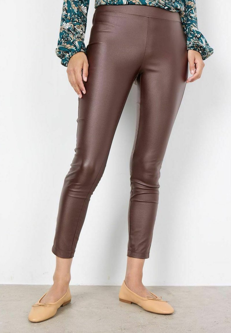 Leggings de imitación cuero marrón con un diseño ajustado y textura suave, combinados con una blusa floral de manga larga y bailarinas beige.