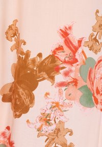 Stoff mit Blumenmuster, das große Blüten in Rosa-, Rot- und Erdtönen zeigt, vor einem sanften beigen Hintergrund.