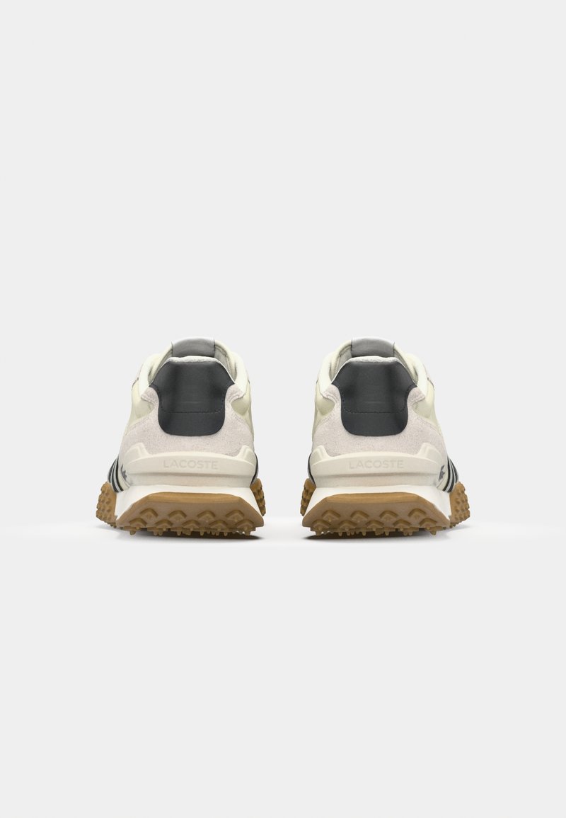 Des chaussures de sport blanches et grises avec une semelle extérieure texturée, des accents noirs et un talon en suède. Elles comportent un logo sur le talon et un col rembourré.