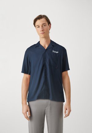 Camicetta a maniche corte blu navy con design a bottoni, taschino sul petto e logo ricamato. Realizzata in tessuto liscio, presenta un colletto classico.