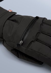 Svart isolerad jacka med dragkedjeförsedd ficka, quiltad design och mjuk yta. Den har en liten märkesetikett som accent.