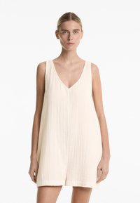 Cremefarbenes ärmelloses Kleid mit V-Ausschnitt, aus strukturiertem Stoff. Lockere Passform, knielang und mit geradem Saum abgeschlossen.