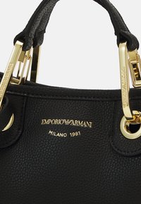 Czarna skórzana torba z fakturowaną powierzchnią, złotym okuciem i detalem z logo "Emporio Armani Milano 1981".