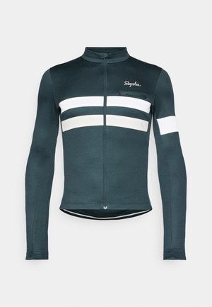 Maillot de cyclisme à manches longues de couleur vert foncé, avec des rayures horizontales blanches et des accents texturés. Fermeture éclair quart de zip à l'avant, en tissu extensible.