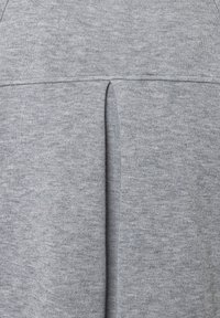 Grijze sweatshirtstof heeft een subtiele textuur met een gemiddelde split aan de achterkant, wat een gelaagd designelement biedt.