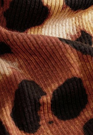 Stickad tyg med ett abstrakt mönster av stora svarta fläckar på en gradientbakgrund av varma bruna och krämiga nyanser. Texturerad yta.
