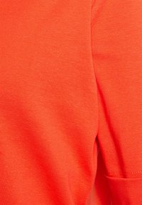 Tričko s krátkým rukávem, kulatým výstřihem v jasně oranžové barvě, vyrobené z hladké bavlněné směsi; obsahuje boční kapsu a jemně žebrovanou texturu.