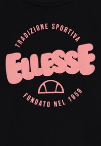 Melnas auduma T-krekls ar lieliem rozā burbuļveida burtiem "Ellesse" un izliekto tekstu. Ietver "Tradizione Sportiva" un "Fondato nel 1959."