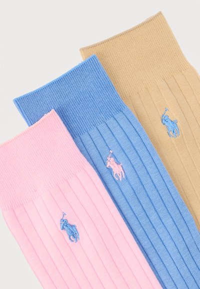 Τρεις ριμπ πλεκτές κάλτσες πληρώματος σε μπεζ, μπλε και ροζ, καθεμία με ένα αντίθετο κεντημένο λογότυπο παίκτη πόλο κοντά στη μανσέτα.