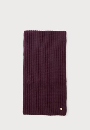 Écharpe en tricot côtelé violet foncé pliée avec un petit emblème doré rond près d'un bord sur un fond clair.