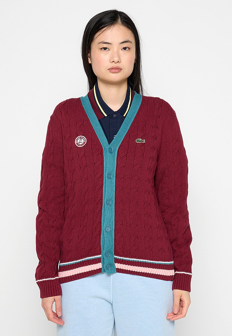 Cardigan bordeaux en tricot torsadé avec des accents en bleu canard, col en V, fermeture à boutons et ourlet rayé. Présente un logo brodé sur la poitrine gauche.