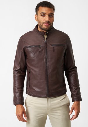 Brown leather jacket with a stand collar, two zippered chest pockets, and zippered side pockets. Smooth texture, fitted silhouette.