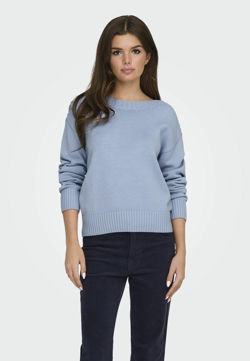 Light blue knitted sweater with a round neckline, long sleeves, and ribbed cuffs and hem. Worn with dark pants, smooth texture.