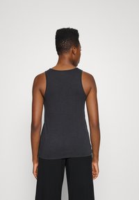Camisola sem mangas preta com decote redondo, feita de um tecido macio. Apresenta um corte descontraído e uma textura suave, sem padrões visíveis.