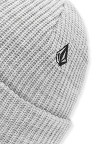 Grijze gebreide beanie met een geribbelde textuur, voorzien van een klein zwart logo aan de zijkant. Het ontwerp is eenvoudig en gestructureerd voor warmte.