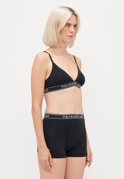 Čierny rebrovaný bralet s nastaviteľnými ramienkami a elastickým pásom s logom. Skladá sa z čiernych boxerkových šortiek s podobným brandingom.