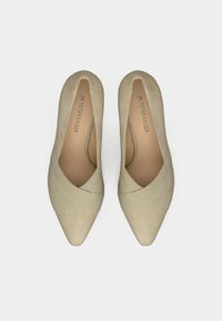 Chaussures à talons hauts en daim beige avec un bout pointu, présentant des détails de design croisés sur la tige, une texture lisse et une doublure en cuir.