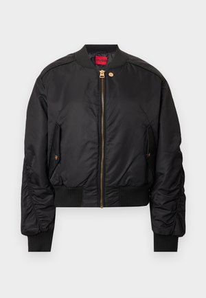 Veste bomber noire avec une fermeture éclair à l'avant, un col et des poignets côtelés, des poches latérales et des accents de quincaillerie dorée. Texture extérieure lisse.