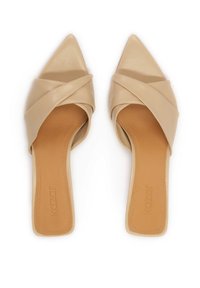 Beige, puntige mules met kruislings leren banden. De binnenzool is glad en heeft een tan kleurige inlegzool met subtiele branding.