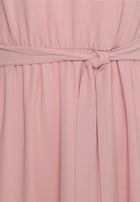 Roze jurkstof met een geknoopte tailleband, plooitexturen en zachte draping. Het materiaal lijkt licht en soepel te zijn.