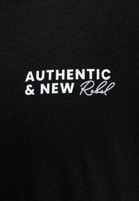 Tissu noir avec texte blanc et gris indiquant « AUTHENTIC & NEW Rebel » en deux polices distinctes.