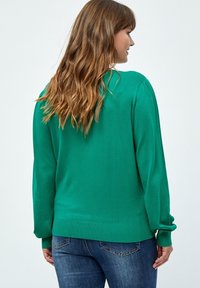Grüner Pullover, aus weichem Strickmaterial, mit langen Ärmeln und lässiger Passform, hat eine glatte Textur und einen gerippten Saum.