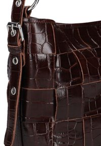 Bruine handtas met krokodillenprint en glanzende afwerking, met zilveren hardware en een leren schouderriem. Structuurdesign met textuur.