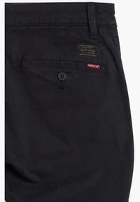 Pantalon noir Levi's montrant une poche arrière avec bouton, passants de ceinture et deux petites étiquettes de marque au-dessus de la poche.