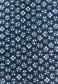Tessuto blu navy con un motivo ripetuto di cerchi concentrici in azzurro chiaro e bianco. Texture liscia e design uniformemente distribuito.