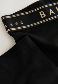 Črne tkaninske hlačke z črnim elastičnim pasom, ki ima zlat šiv in delno vidno blagovno znamko "BAKER".