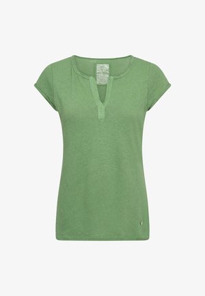 Groen dames top met korte mouwen, een ronde uitsparing in de halslijn en een klein metalen logo vlak bij de zoom aan de voorkant aan de linkerzijde.