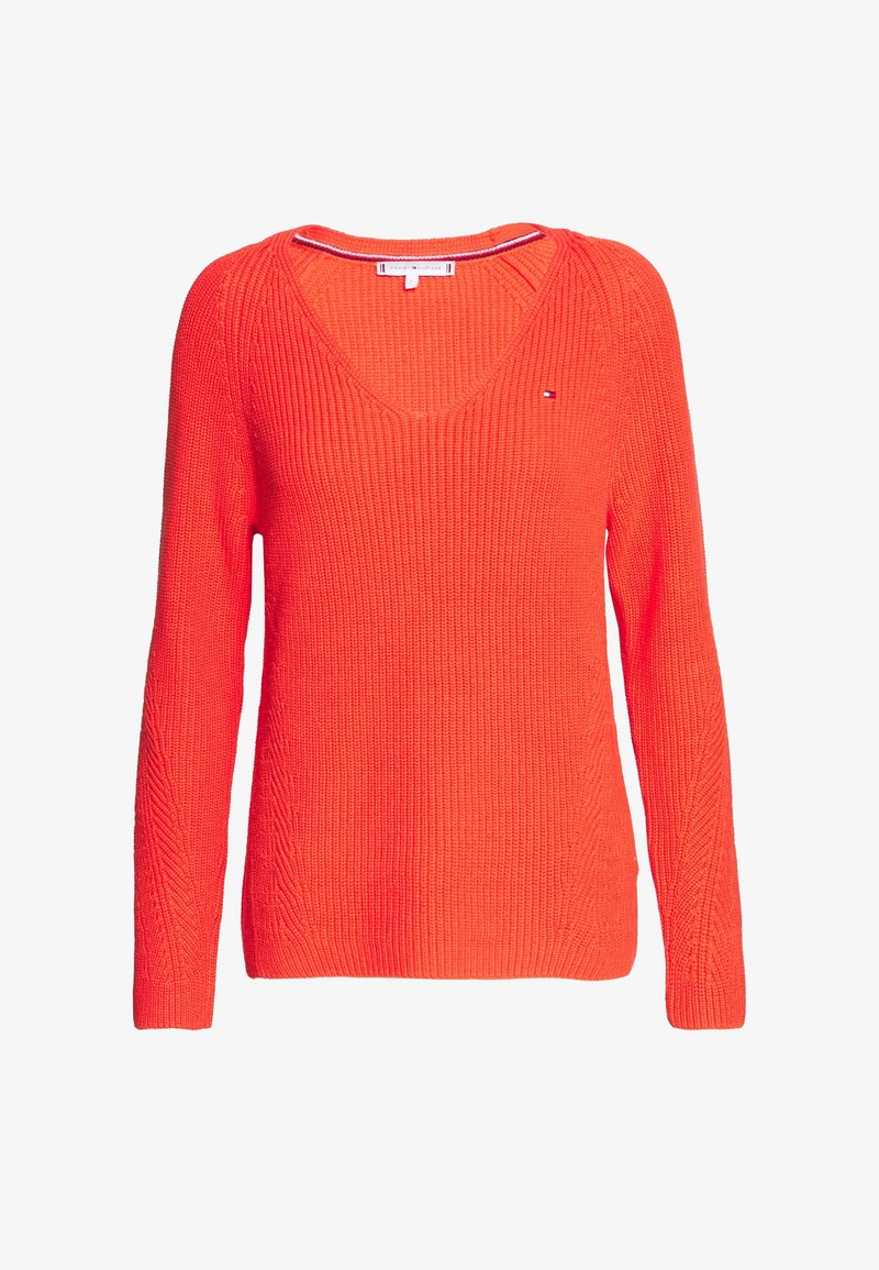Pull tricoté orange vif à manches longues, col en V et logo discret de la marque sur la poitrine côté gauche.